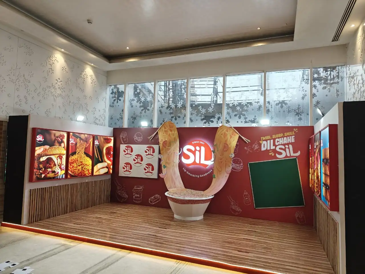Immersive brand experience zone with custom exhibition booth, 3D product installation, illuminated logo signage, and digital displays